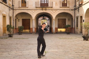 Sakallı, at kuyruklu, siyah şeffaf gömlekli, siyah benekli, siyah pantolonlu ve ceketli, şehirde flamenko dansı yapan genç bir adam. Sanat, dans, kültür, gelenek.