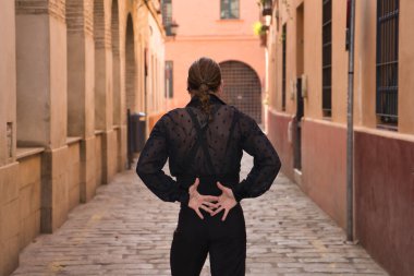 Sakallı, at kuyruklu, siyah şeffaf gömlekli, siyah benekli, siyah pantolonlu ve ceketli, şehirde flamenko dansı yapan genç bir adam. Sanat, dans, kültür, gelenek.