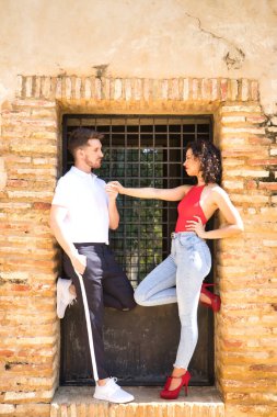 Birbirine aşık genç bir çift, şehvetli bir tavırla birbirlerinin gözlerinin içine bakıyor, ızgarayla bir kapının tuğla kenarına yaslanıyorlar. Aşk, tutku, arzu, aşıklar, sevgililer günü. Dikey konum.