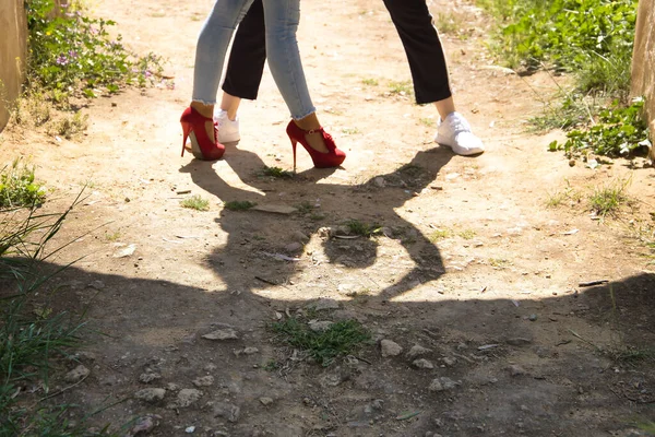 Feet and shadow of a young couple dancing sensual bachata under an ancient stone arch in an outdoor park. Latin, sensual, folkloric, urban dance concept.