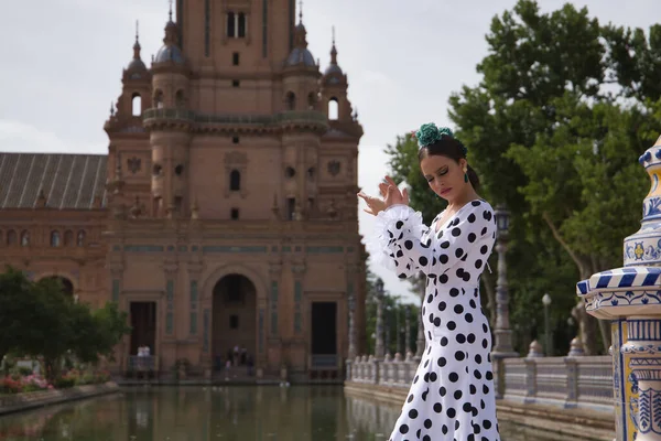 Siyah benekli, saçında yeşil karanfil olan, gölün kenarında flamenko dansı yapan beyaz dans kıyafetli genç bir kadın. Flamenko konsepti, dans, sanat, tipik İspanyol dansı.