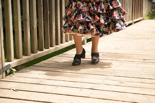 Detail of black flamenco dance shoes of young woman with black skirt with flowers on a wooden bridge. Flamenco concept, dance, art, typical Spanish dance, shoes.