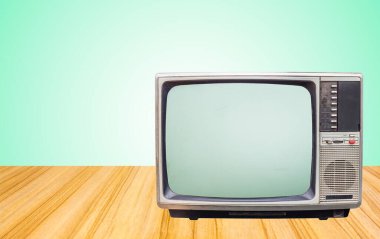 Masanın yanındaki eski televizyon alıcısı yeşil duvar arka planında.