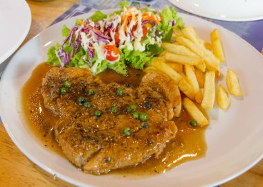 Restoranda taze sebze salatası ve patatesle ızgara domuz eti. Odak noktasını seç..