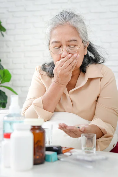 Asian elderly woman stay home to prevent infection During the coronavirus epidemic She was sick with a fever and took medication to treat the virus. Home isolation concept, stay at home