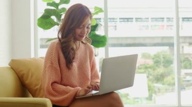 Güzel Asyalı kadın evde oturuyor ve oturma odasında çalışıyor. Modern iletişim teknolojisi konsepti, sosyal uzaklık, evden çalışma, yeni normal