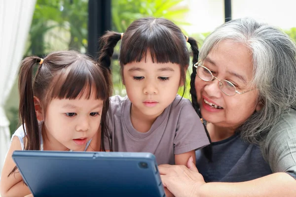 亚洲祖母和两个孙女在平板电脑上在线学习 验尸官大流行期间的在线教育 家庭隔离 家庭概念 — 图库照片