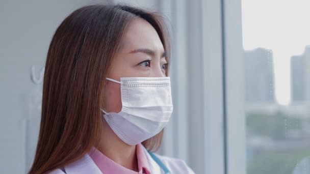 Médico Asiático Vistiendo Una Máscara Blanca Pie Ventana Mira Gente — Vídeo de stock
