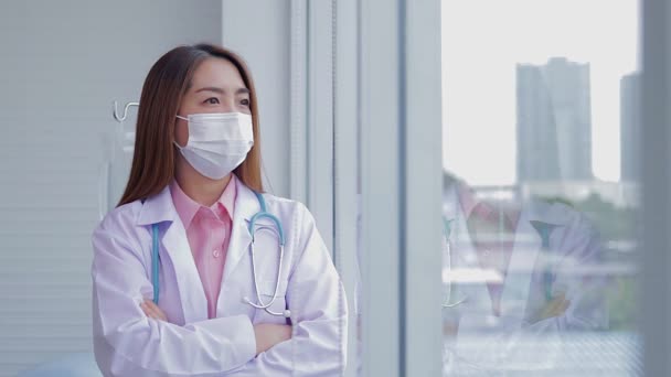 Asijská Doktorka Bílé Masce Rukama Zkříženýma Okně Podívejte Lidi Venku — Stock video