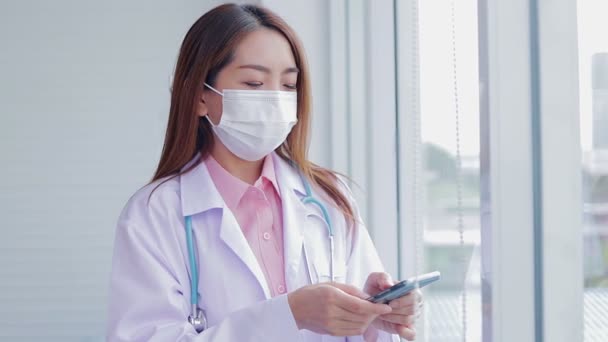 Krásná Asijská Žena Lékař Sobě Bílé Masky Stojan Drží Smartphone — Stock video