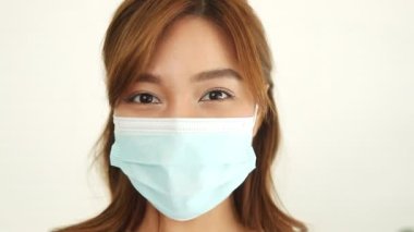 Asyalı uzun saçlı güzel kadın koronavirüs (COVID-19) ve gribe karşı koruyucu bir maske takar. Enfeksiyon bulaşmasını azaltmak için sağlık hizmeti kavramı.