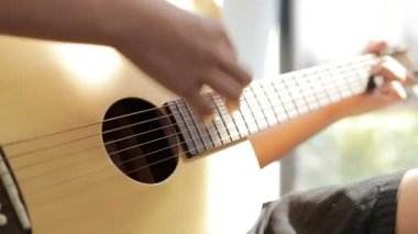 Sabahleyin evde akustik gitar çalan Asyalı çocuk müzikten memnun. Uluslararası müzik eğitimi kavramı öğrenme ve uygulama