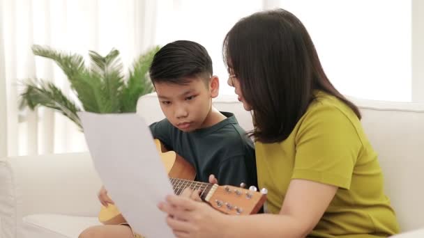 Mãe Asiática Filho Sentado Sofá Branco Casa Filho Toca Guitarra — Vídeo de Stock