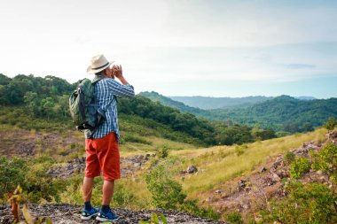 Yaşlı Asyalı bir adam yüksek bir dağda yürüyüş yapıyor ve güzel doğal manzaraya bakıyor. Emeklilik çağındaki doğal turizm kavramı. Boşluğu kopyala