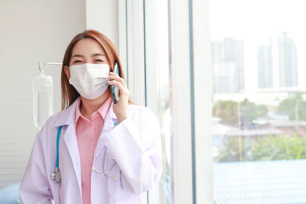 Hermosa Médica Asiática Con Una Máscara Blanca Sostenga Teléfono Inteligente — Foto de Stock