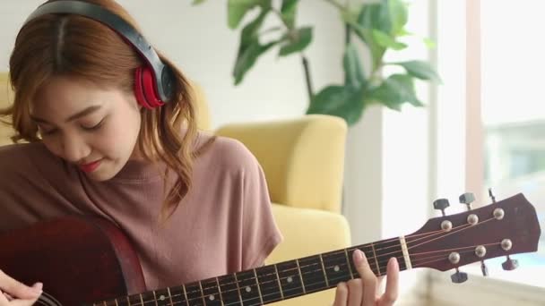 Μια Όμορφη Ασιάτισσα Παίζει Κιθάρα Στο Σαλόνι Του Σπιτιού Της — Αρχείο Βίντεο