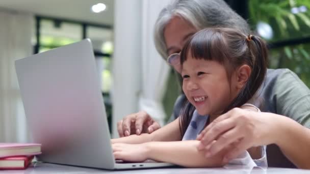远程教育的概念从家里上网学习 亚洲祖母和孙女通过笔记本电脑在网上学习 — 图库视频影像