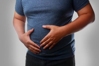 Koca göbekli şişman adamın mide ağrısı var. Kolon kanseri özofajiyal kanser ve mide kanseri, yağlı karaciğer, diyabet, yüksek tansiyon anjini hiperlipidemisi riski var. obezite tehlikesi kavramı