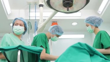 Asyalı cerrahlardan oluşan profesyonel bir ekip hastane ameliyathanesinde yatakta yatan bir hastaya ameliyat yapıyor. Tıbbi kavramlar. acil ameliyat