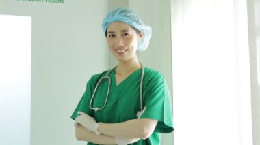 Ameliyathanenin önünde duran Asyalı profesyonel kadın cerrah hastayı başarılı bir şekilde ameliyat ettikten sonra gülümsedi. Hastanelerde tıbbi konseptler. Estetik ameliyat.