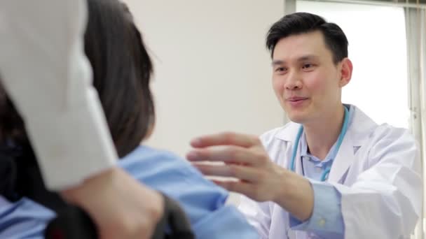 Ασιάτης Γιατρός Εξετάστε Συμπτώματα Ενός Ασθενούς Που Κάθεται Αναπηρικό Καροτσάκι — Αρχείο Βίντεο