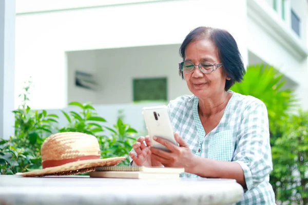 elderly woman living at home holding a smartphone to talk online through the application She smiled happily. Social concepts of the elderly in retirement age. use of modern communication technology