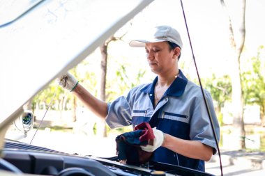Asyalı oto tamirci motor yağını ve arabanın çeşitli sistemlerini kontrol et. Bu hizmeti kullanmaya gelen müşterilere. Araba bakımı denetimi ve sigortası kavramı. araba garajı