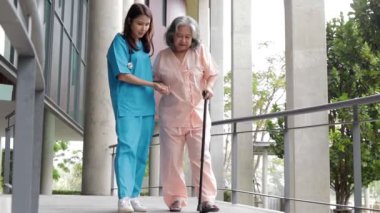 Cerrahi önlük giyen bir kadın doktor yaşlı bir hastayla ilgileniyor. Vücudu güçlendirmek için fizyoterapi yapılmasına yardımcı olur. Hastanede tıbbi hizmet kavramı
