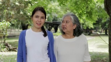 Mutlu Asyalı kızı olan yaşlı bir anne parkta yürüyüş yapıp egzersiz yapıyor. Aile konsepti, sağlık hizmeti. Yaşlı bakıcı