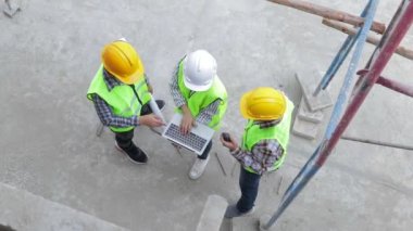 Mühendisler ve inşaat müteahhitleri dışarıda inşaat planlarını tartışmak için dizüstü bilgisayar tutuyorlar. Emlak projesi kavramları, inşaat işbirliği.