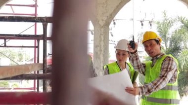 Mimarlar, Mühendisler ve İnşaatçılar açık alanda inşaat planlarını tartışan bir planı ellerinde tutuyorlar. Emlak projesi kavramları, inşaat işbirliği.