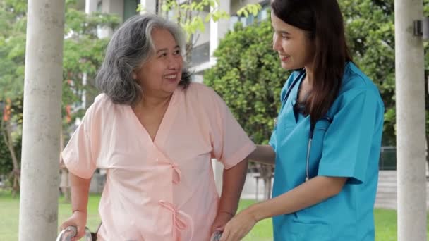 外科用ガウンを着た女性医師が高齢者の世話をする 体を強くするために物理的な療法を行うために歩くをサポートします 病院での医療サービスの概念は — ストック動画