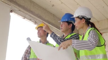 Mimarlar, Mühendisler ve İnşaatçılar inşaat planlarını tartışan bir planı ellerinde tutuyorlar. Emlak projesi kavramları, inşaat işbirliği.