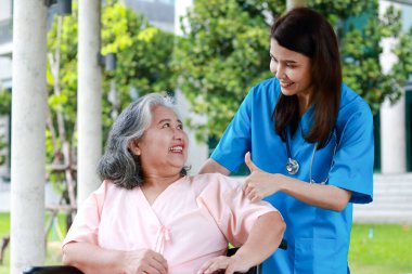Asian female doctor treats an elderly patient sitting in a wheelchair. Concept of medical services in hospitals. surgical treatment of patients