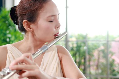 Asian woman blowing the flute, a universal classical instrument. The concept of a classical music school. music teacher