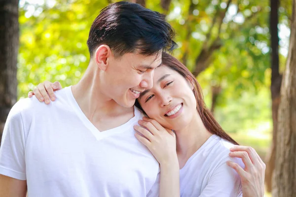 Asian couple wearing white shirts Happy smiling in the park. Family concept. Healthy health care. outdoor exercise