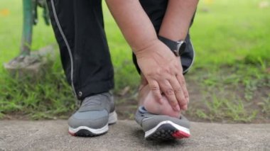 Elderly people have ankle pain after exercising. Massage with your hands to relieve pain. sports concept Elderly health care