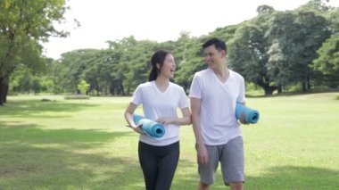 An Asian couple walks and talks after their workout in the park. sports concept health care