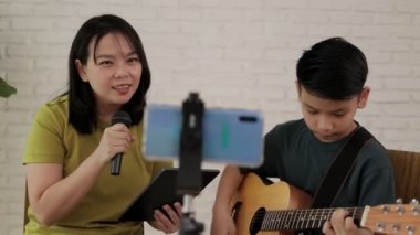 Mother and son sang and played music together and recorded videos on their smartphones. Online music concept. Online music performances. Family relationship activities