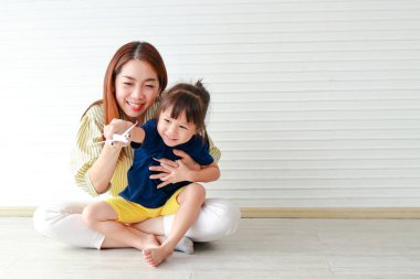 cute mother and daughter Hugging and teasing each other sitting on the floor of the house. Family concept. single mother. copy space