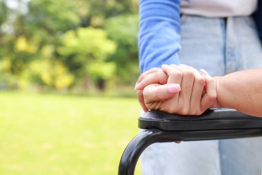 A caregiver shakes hands of an elderly person sitting on a wheelchair. Nursing concepts to take care of elderly health care, senior health rehabilitation center. child taking care of old mother
