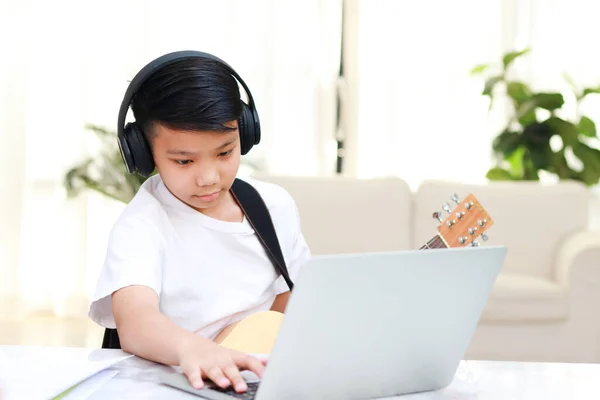 在网上学习音乐的亚洲男孩他正在练习弹吉他 音乐学校的概念 儿童教育 — 图库照片