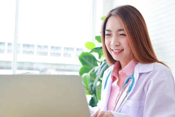 사무실에 아시아 의사는 노트북 컴퓨터 온라인 비디오 통화를 원격으로 환자들에게 — 스톡 사진
