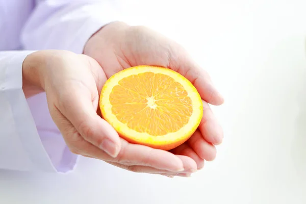 A nutritionist holds an orange. Food concept, benefits of fruit for good health