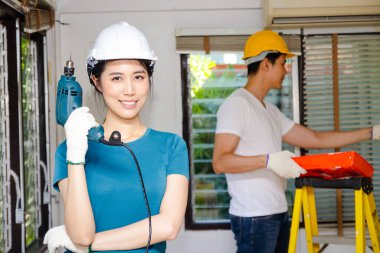 Kask takan Asyalı çiftler evlerini güzel ve yaşanabilir hale getirmek için yenilemeye yardım ediyorlar. İnşaat konsepti, ev inşaatçısı. yeni ev