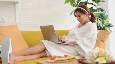 Güzel Asyalı kadın evde spa yapıyor ve ayrıca çalışıyor. Altın ipek bitkisel krem, yüz maskesi, deriyi besler, kolajen ve elastin üretmek için deriyi uyarır. güzellik konsepti