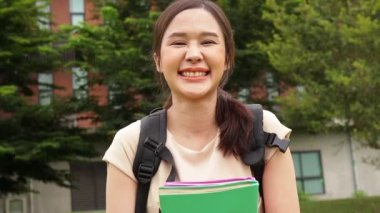 Güzel Asyalı bir kadın kampüste lisans diploması için çalışıyor bir kitap tutuyor ve mutlu bir şekilde gülümsüyor. Eğitici kavramlar. 