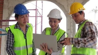 Mühendisler ve inşaat müteahhitleri kapalı alanda inşaat planlarını tartışmak için dizüstü bilgisayar tutuyorlar. Emlak projesi kavramları, inşaat işbirliği.