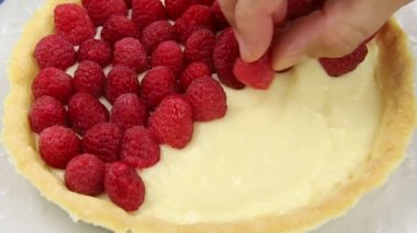 Erkek eli lezzetli bir ahududu turtasını süslüyor.