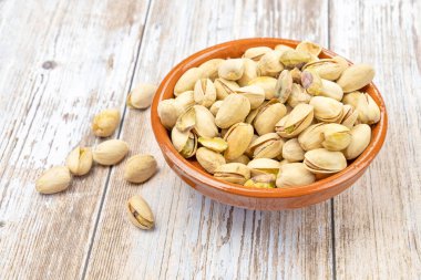 Ahşap arka planda bir kasede fıstık.